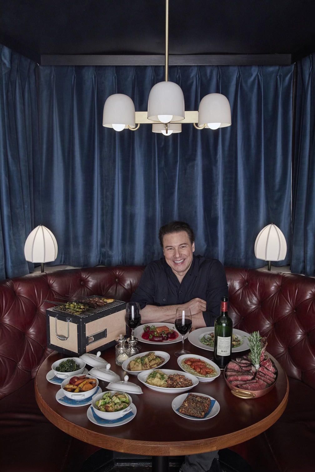 Rocco DiSpirito seated at a table with plates