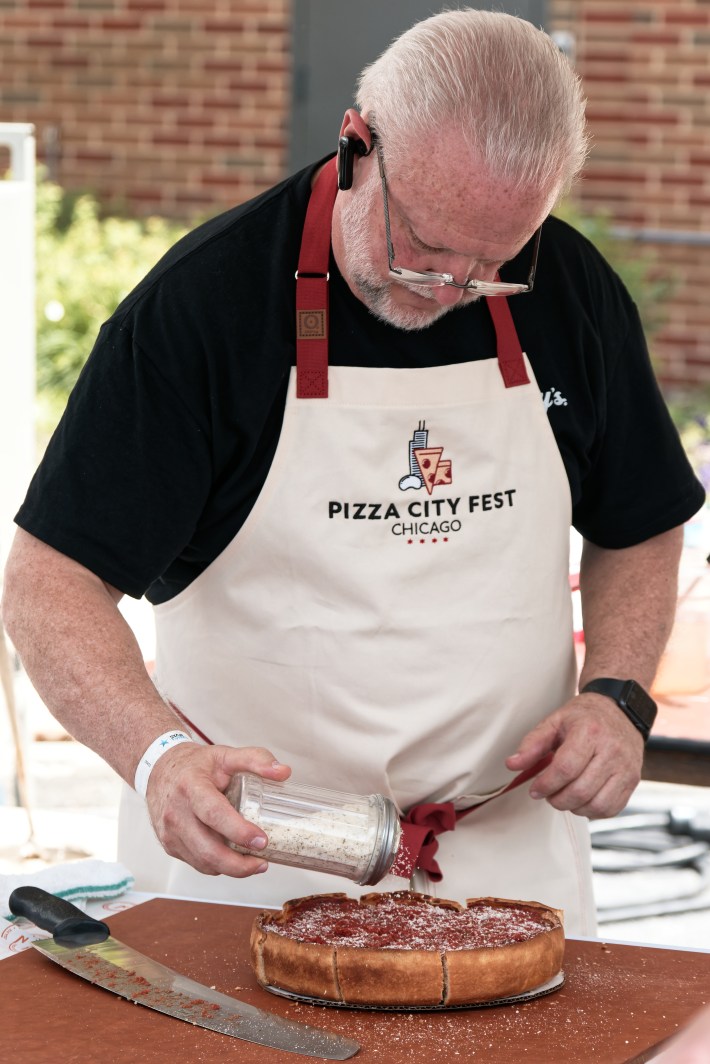 Chef adding cheese to a pizza