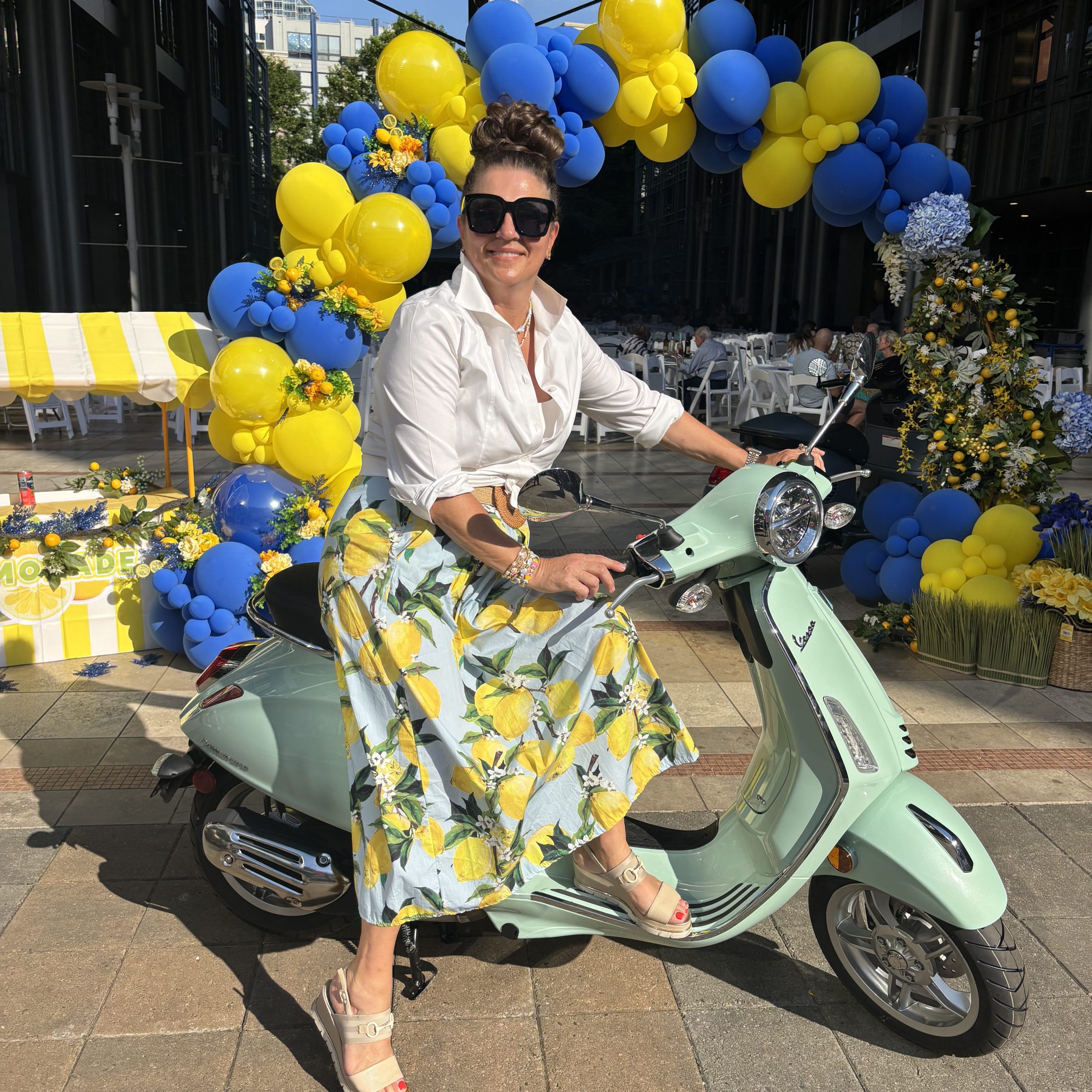 Mandi Casey of Low Country Bella on a foam green Vespa in a floral skirt.