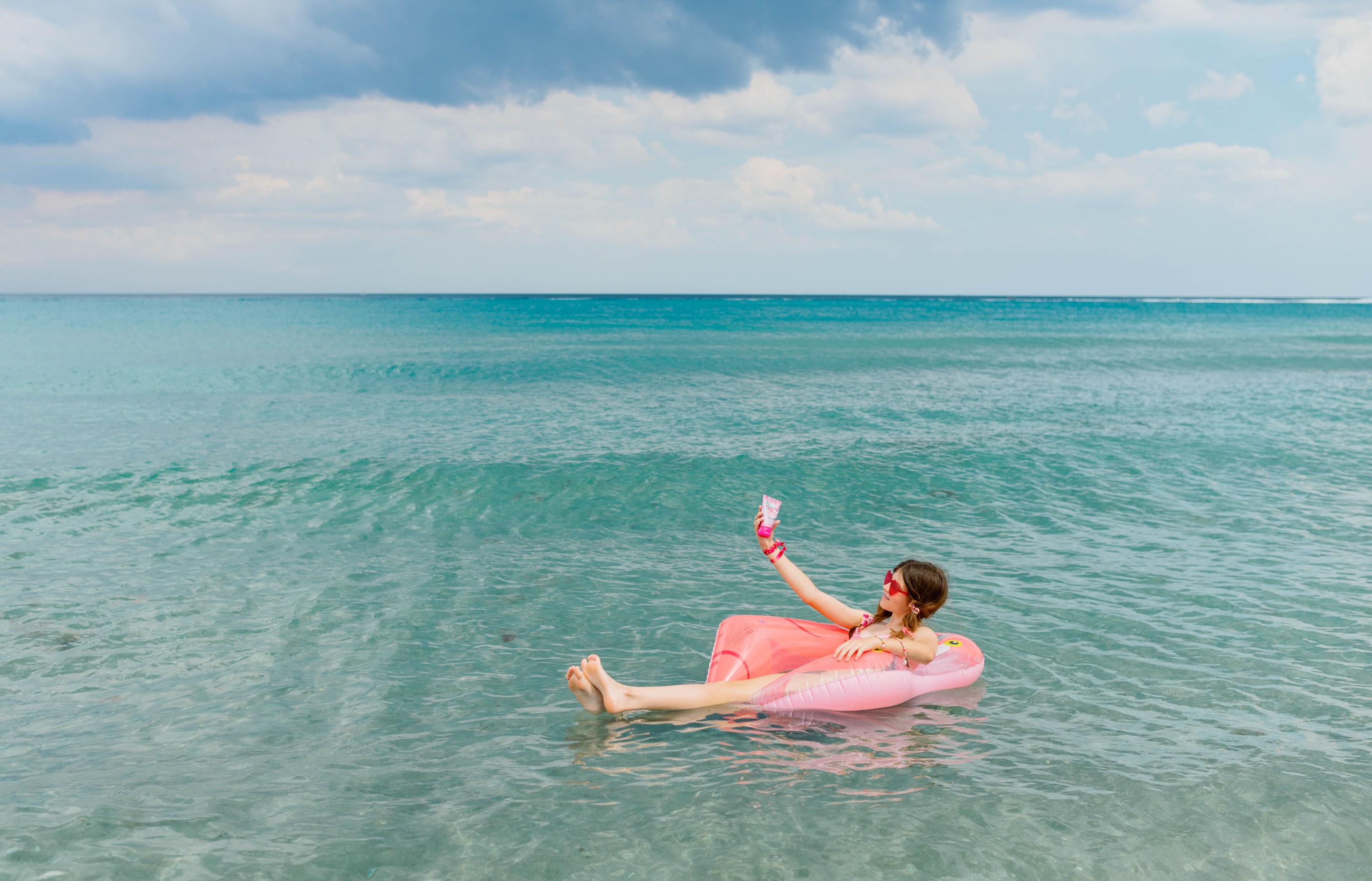 Girl floating in ocean with sunscreen