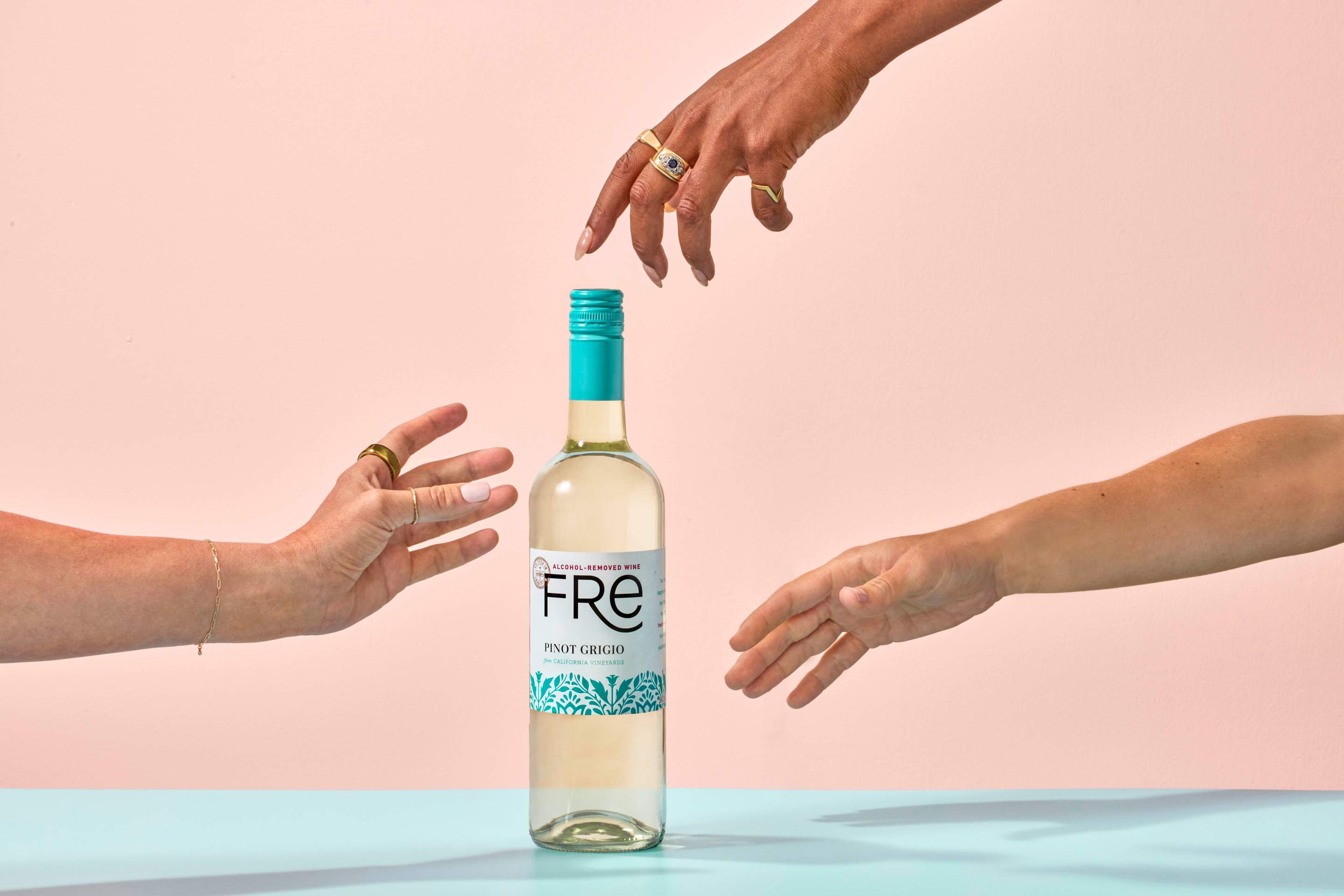 Hands reaching to touch bottle of Fre