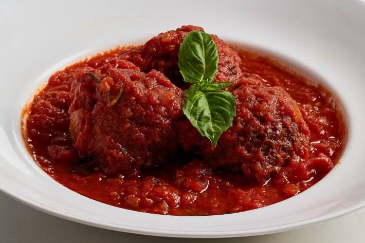 Three meatballs in red sauce with basil