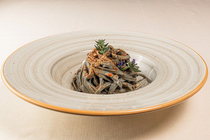Plated tagliolini served in a white bowl with yellow trim at Al Fino.