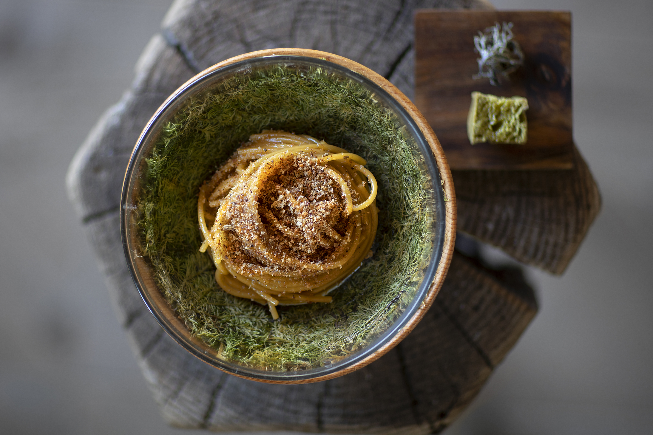 Pasta dish served in a decorative bowl on top of a wooden stump at SanBrite restaurant.