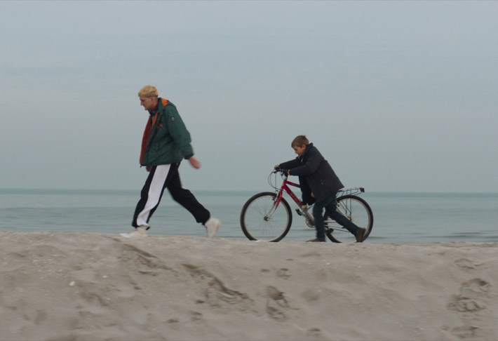 man and boy with bicycle walking on beach