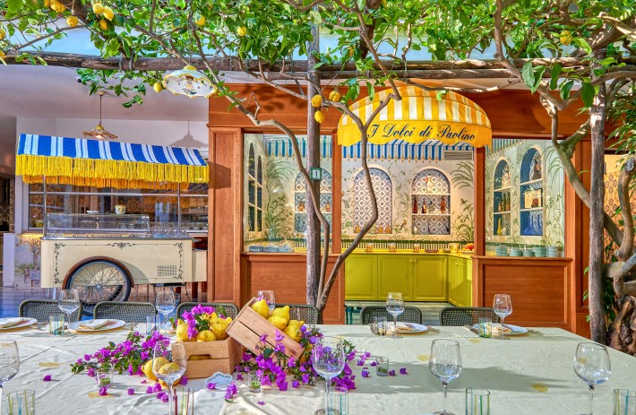 Charming lemon-filled patio at Da Paolino restaurant in Capri, with rustic tables under a canopy of citrus trees.