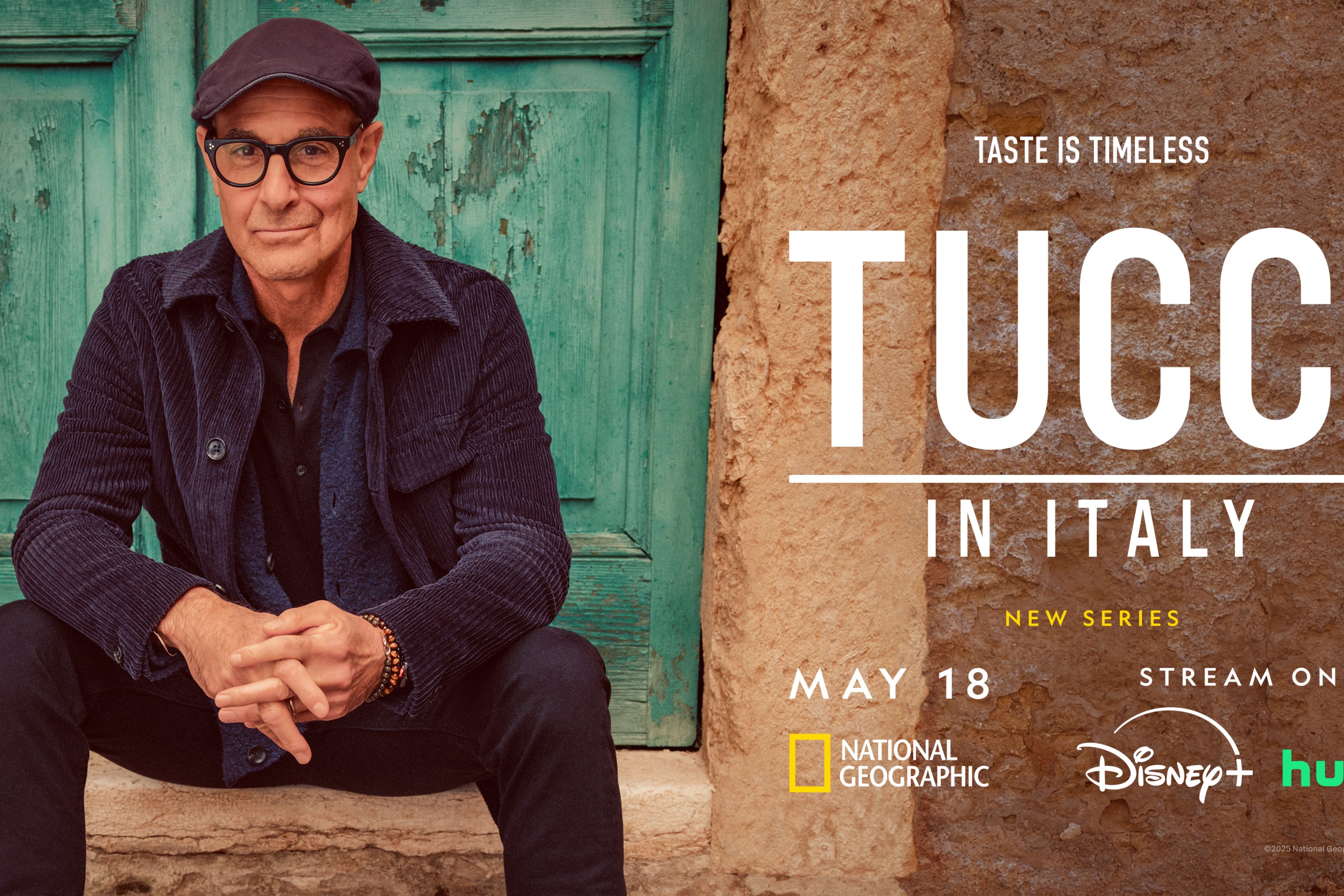 Stanley Tucci wearing a hat, sitting casually on stone steps during filming in Italy.
