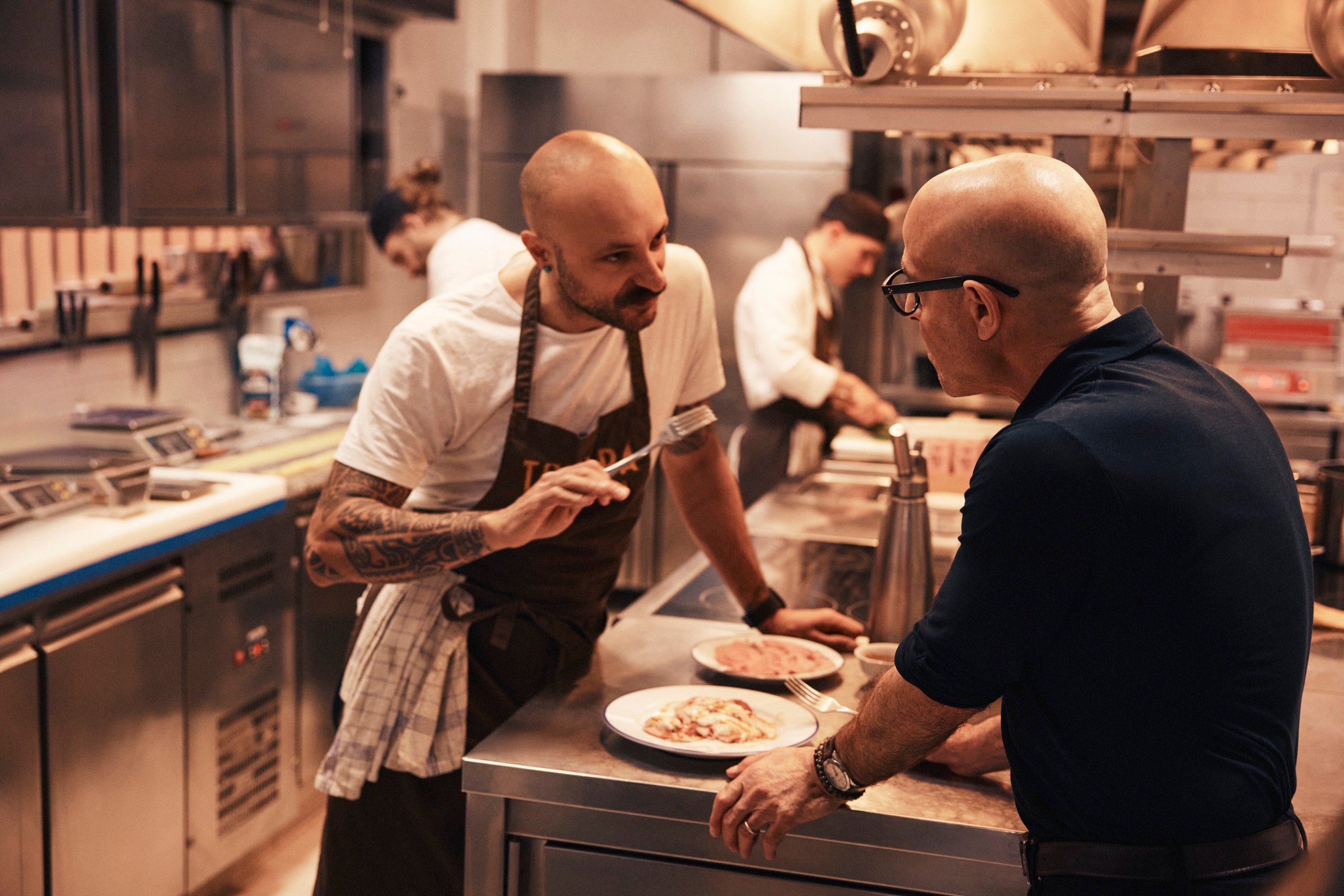 Chef Diego Rossi and Stanley Tucci talk inside the kitchen of Trippa in Milan.
