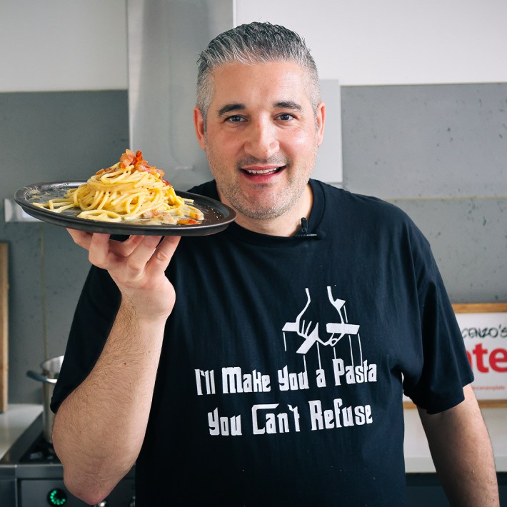 Vincenzo Prosperi holding a plate of carbonara in his kitchen.
