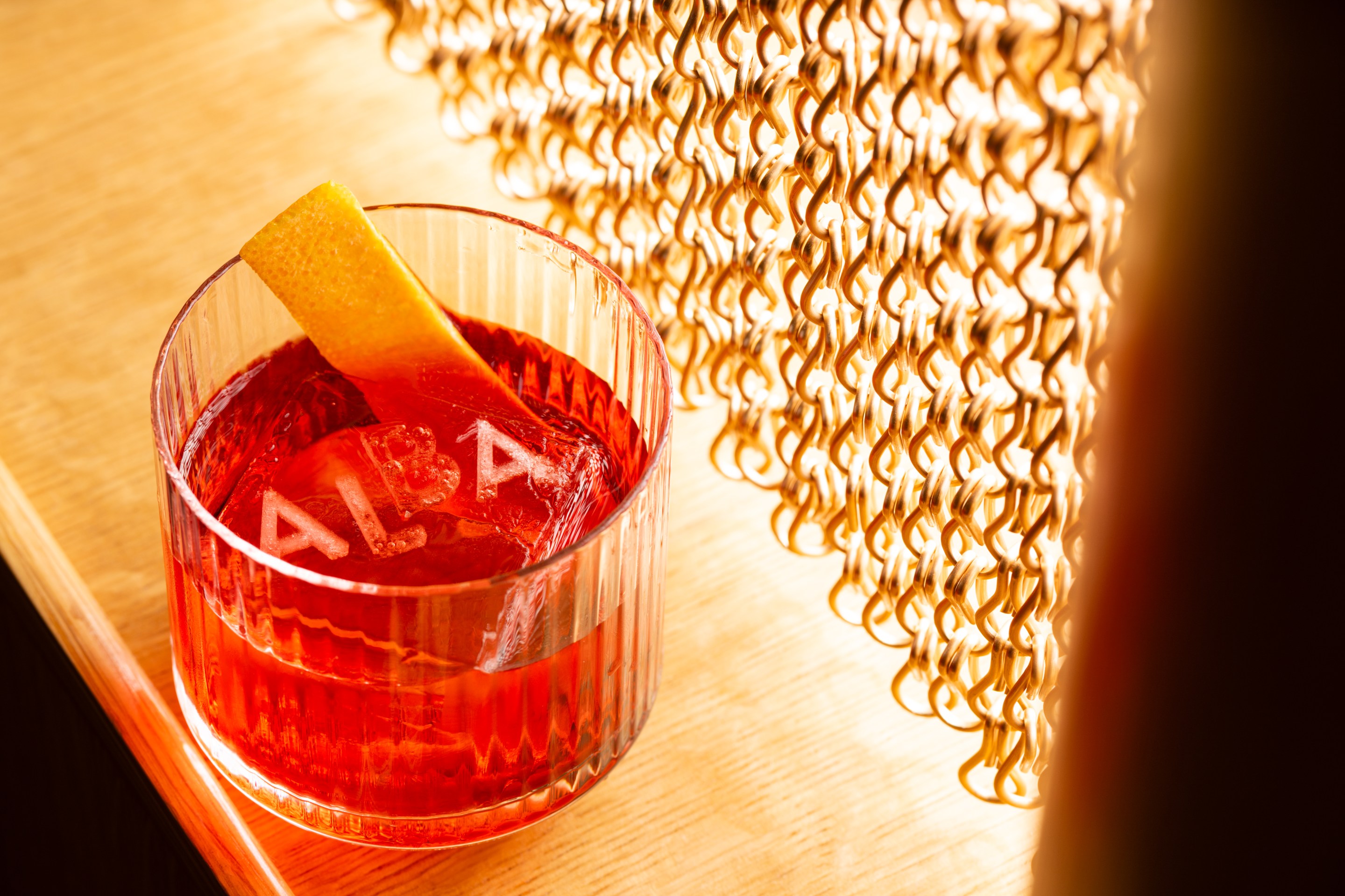 Negroni cocktail with an Alba-etched ice cube and orange twist garnish.