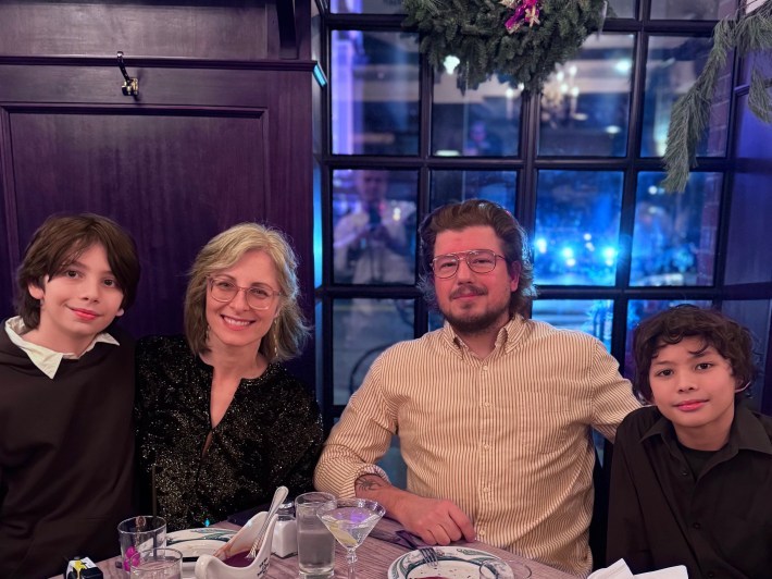 Anthony Falco seated at a table with his wife and two sons, sharing a meal together.
