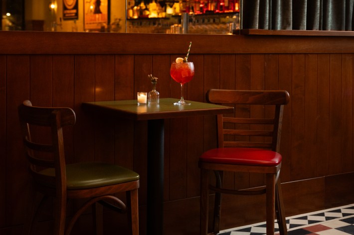 Small table at Bar Bianchi with a red spritz cocktail, candle, and two chairs.