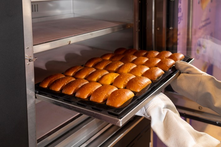 ray of pastries being taken out of the oven by a baker.