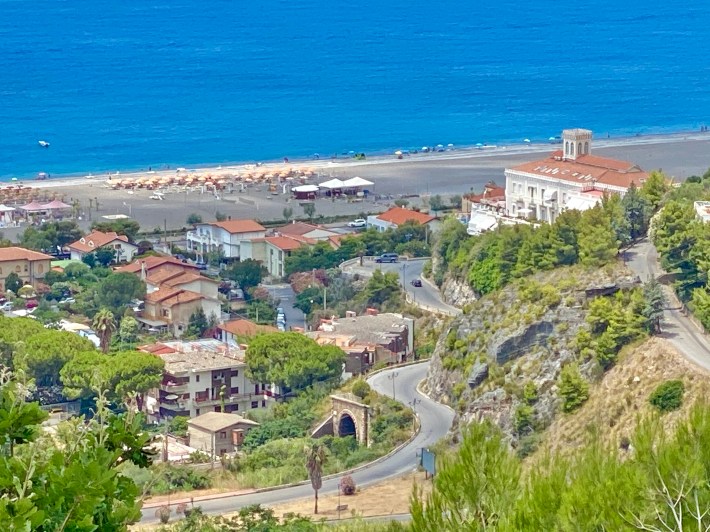 View of Praia a Mare with the beach, ocean, and white villa on a hill.