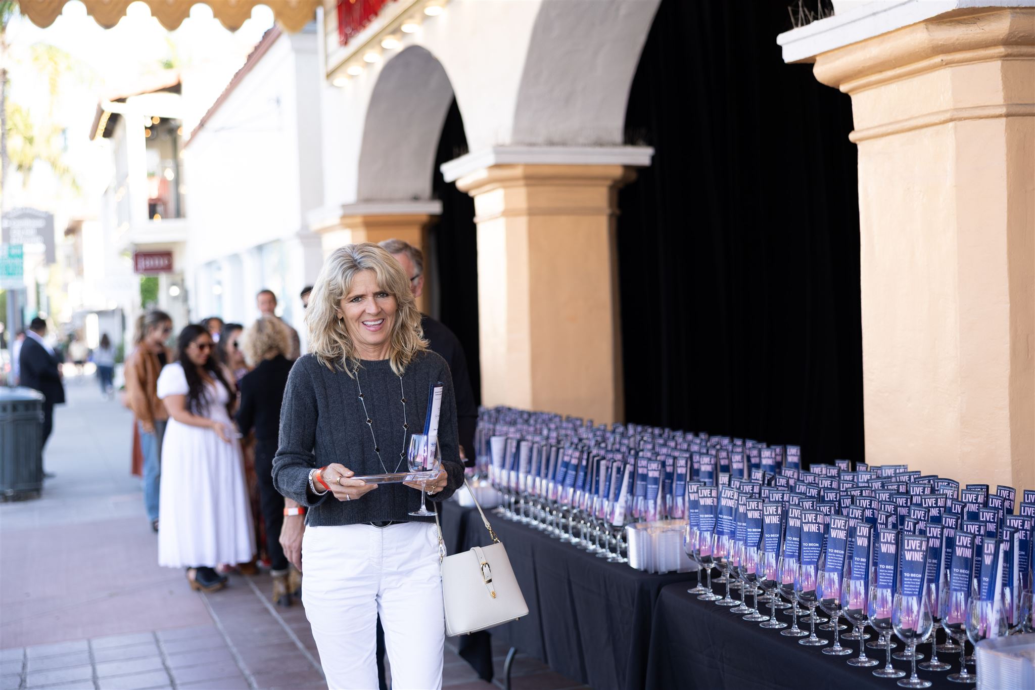 Woman picking up a glass at the start of the Santa Barbara LIVE Art & Wine Tour.
