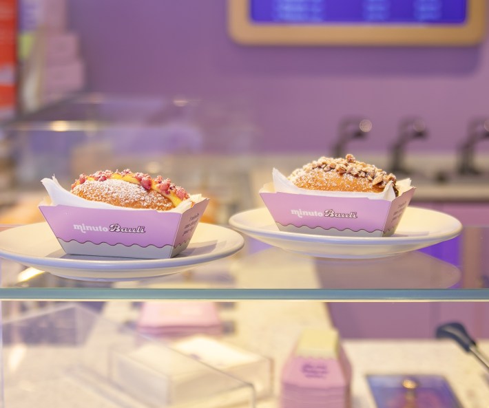 Two filled Minuto Bauli pastries topped with chopped pistachios and berry crumble.