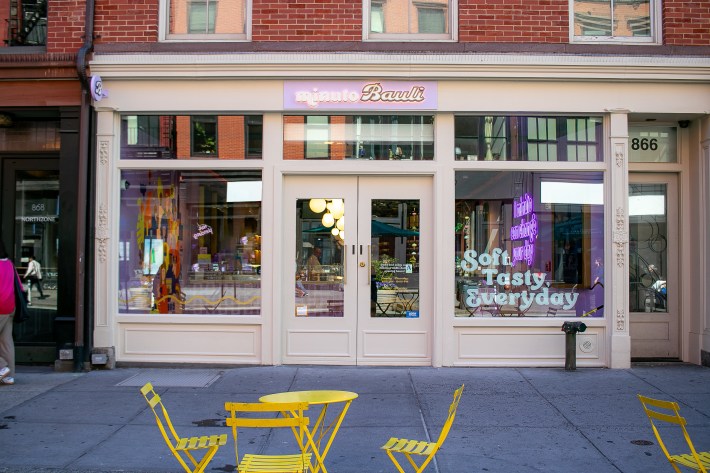 Exterior of Minuto Bauli’s Union Square store with pastel storefront and yellow café chairs.