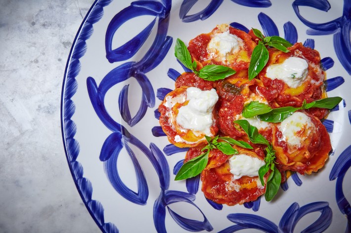 Ravioli topped with tomato sauce, fresh basil, and ricotta.