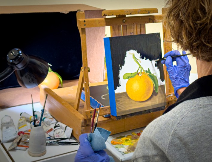 Artist painting a lemon on canvas at a downtown Santa Barbara gallery.