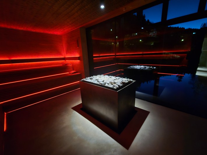 Red lights from the spa surround the wooden spa with windows open to the outside.