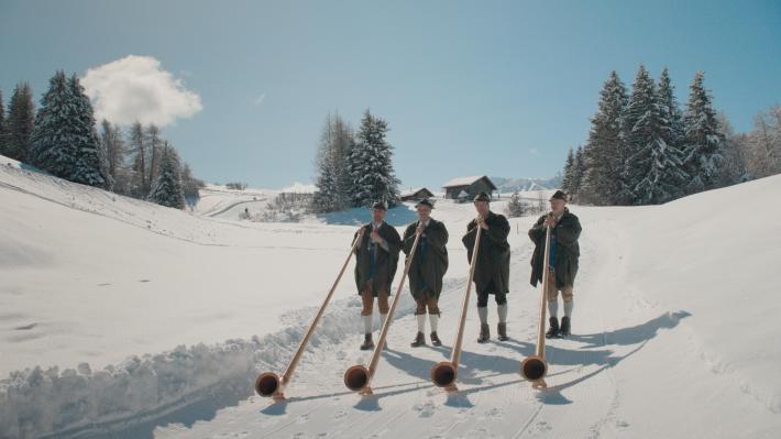 Four horn players on the snow in South Tyrolean.