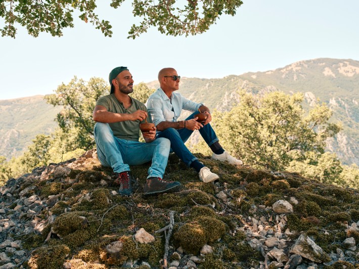 Tucci and chef Nanni enjoying mutton stew with the mountains in the background.