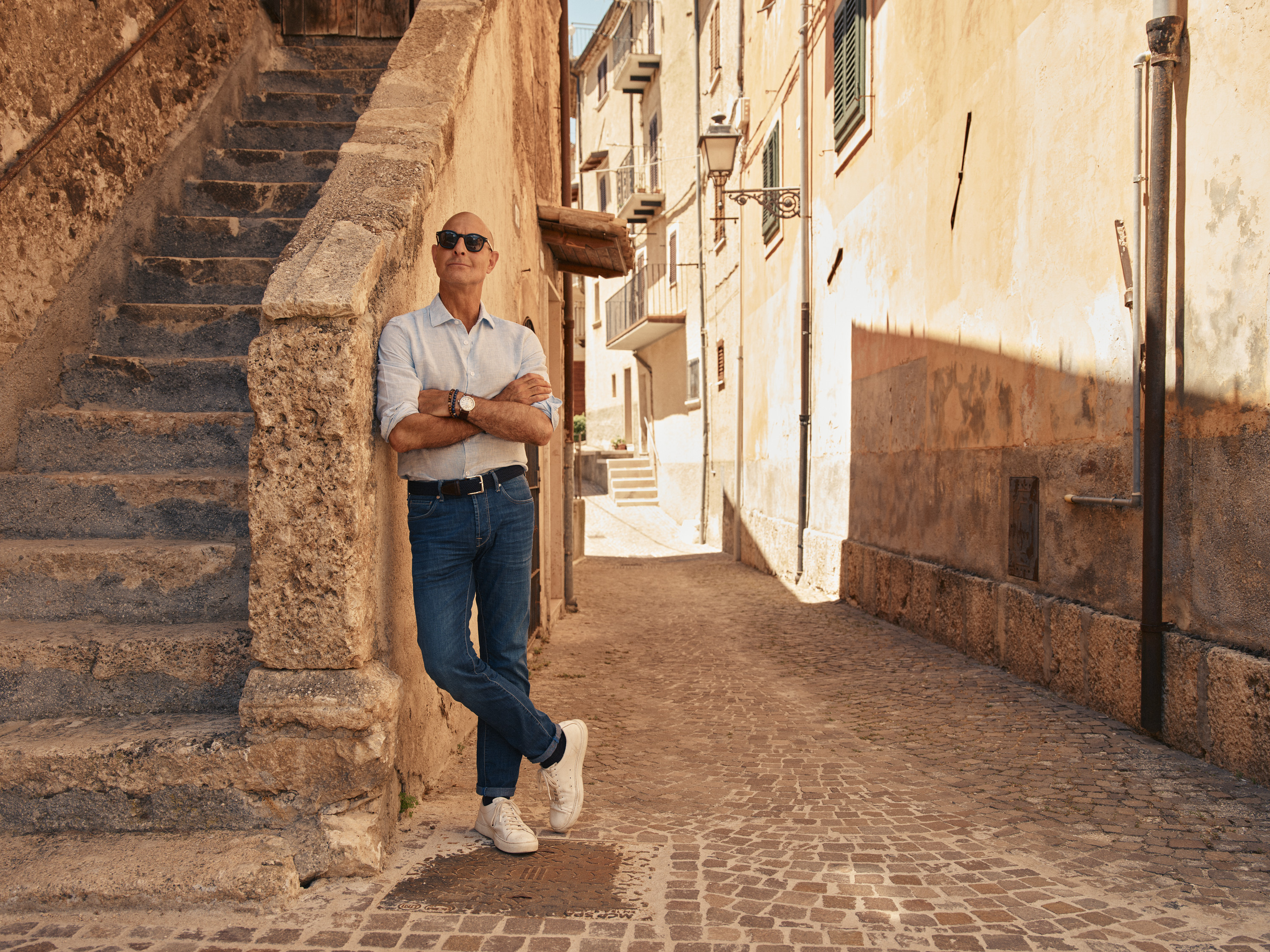 Stanley pondering the old town architecture in Abruzzo, standing against a sprawling staircase.