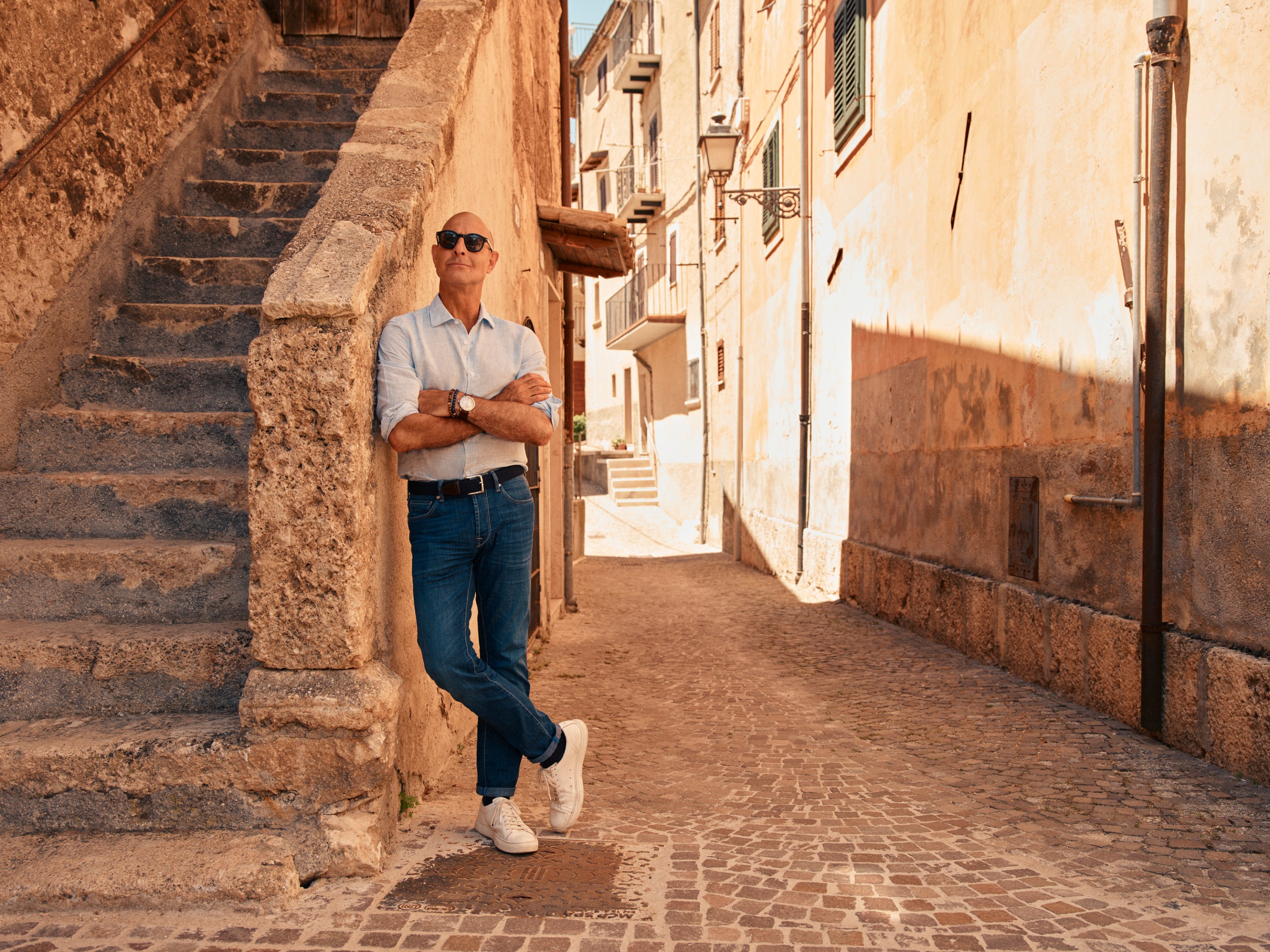 Stanley pondering the old town architecture in Abruzzo, standing against a sprawling staircase.
