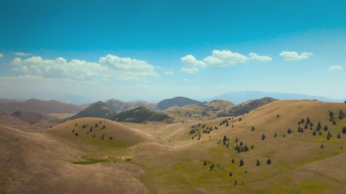 Stunning view of rolling hills, blue skies and white clouds in the background.