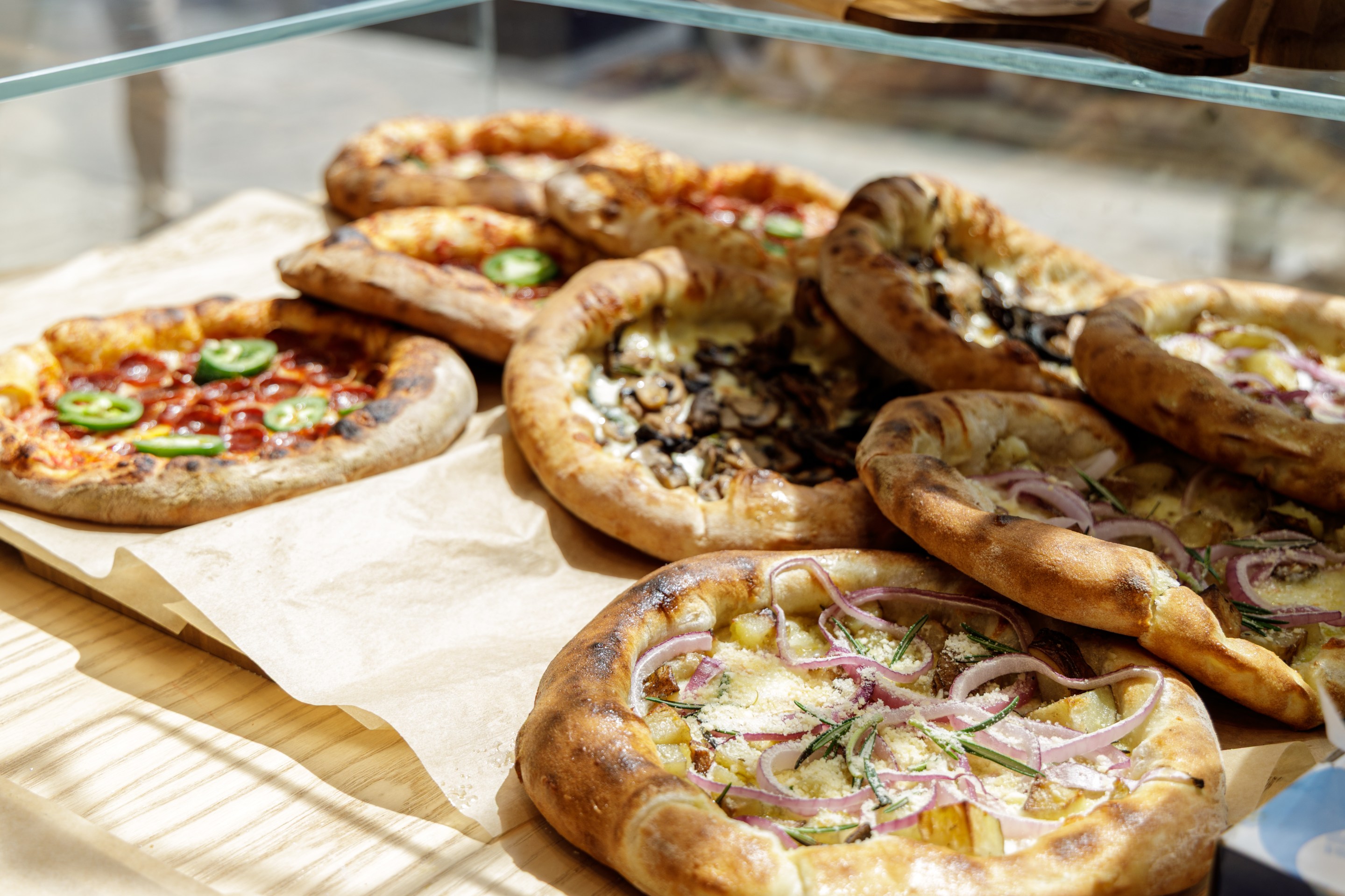 Display case of various mini pizzas at Angelina Bakery.