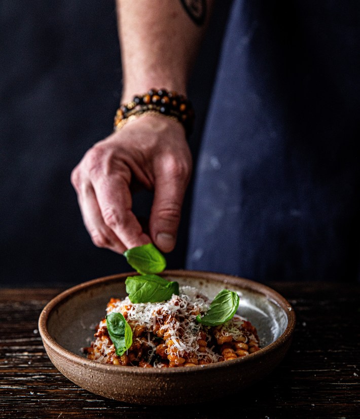Pasta is plated at Cane Pazzo with fresh herbs and cheese