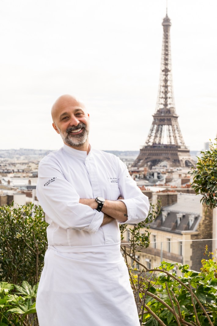 Chef Niko Romito standing on a terrace with the Eiffel Tower in the background
