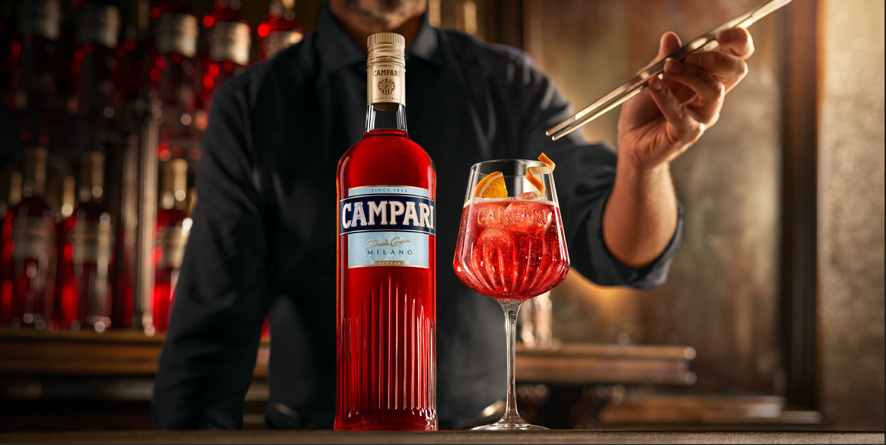 Bartender preparing a Campari Spritz beside a bottle of Campari