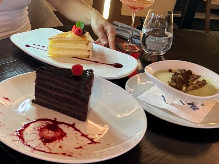 Three desserts including pistachio panna cotta, lemon meringue cake, and seven layer chocolate cake at Serafina Miami