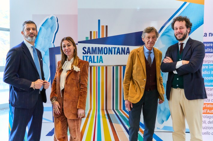Sammontana leadership team standing in front of Sammontana Italia branding wall