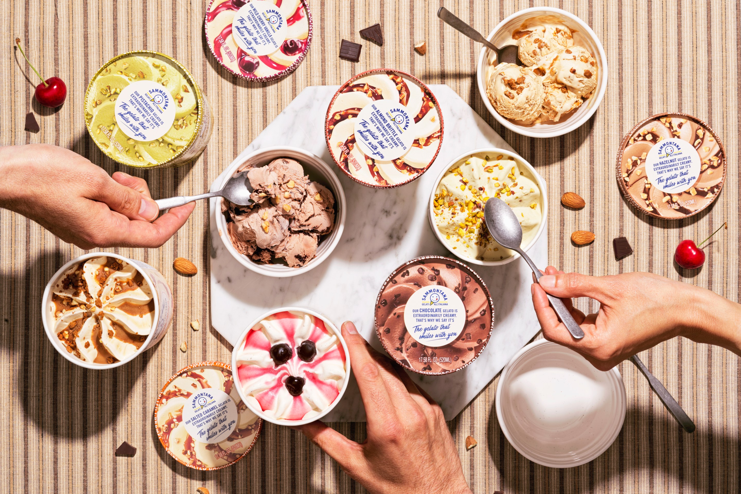 Multiple pints in various flavors, with hands and spoons reaching in.