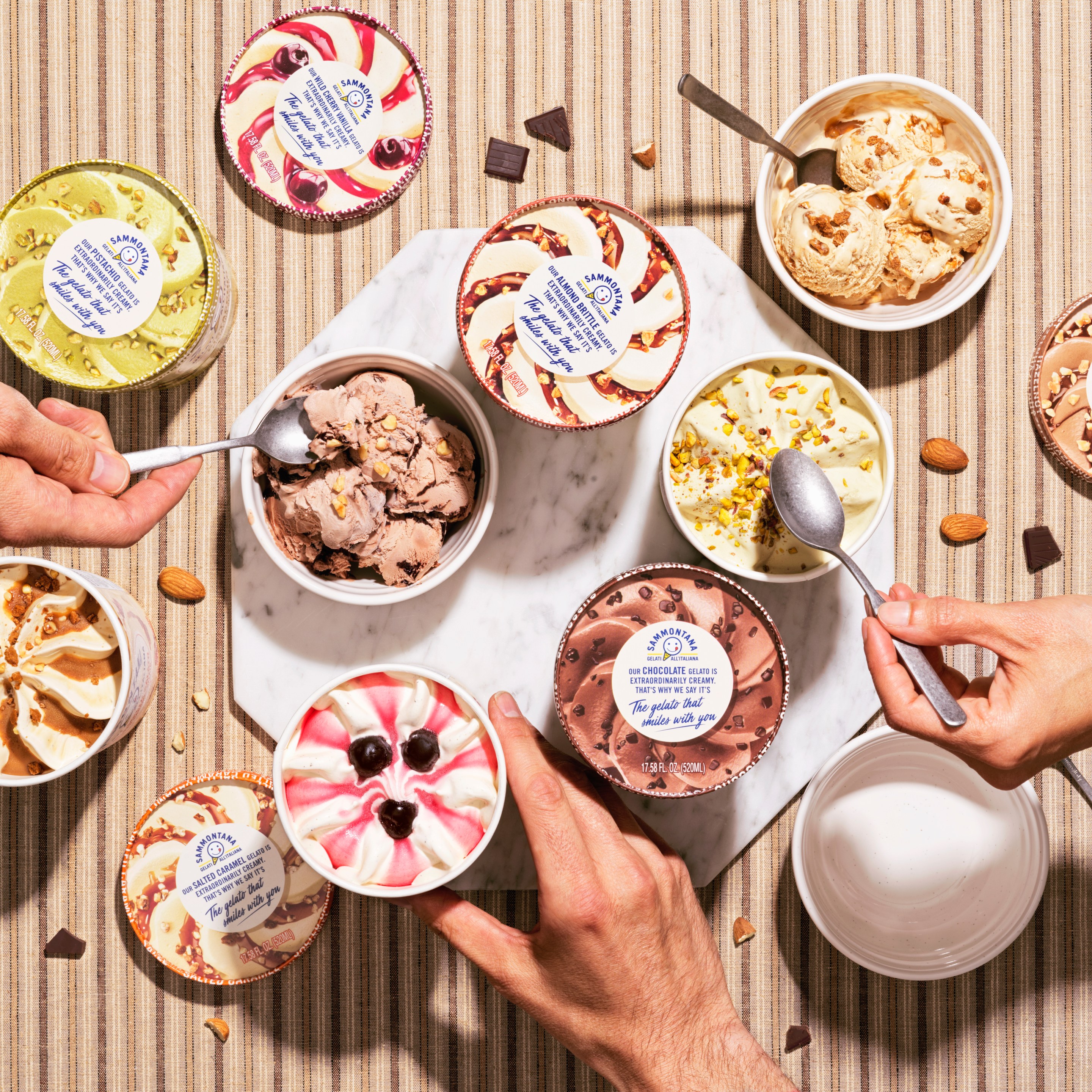 Multiple pints in various flavors, with hands and spoons reaching in.