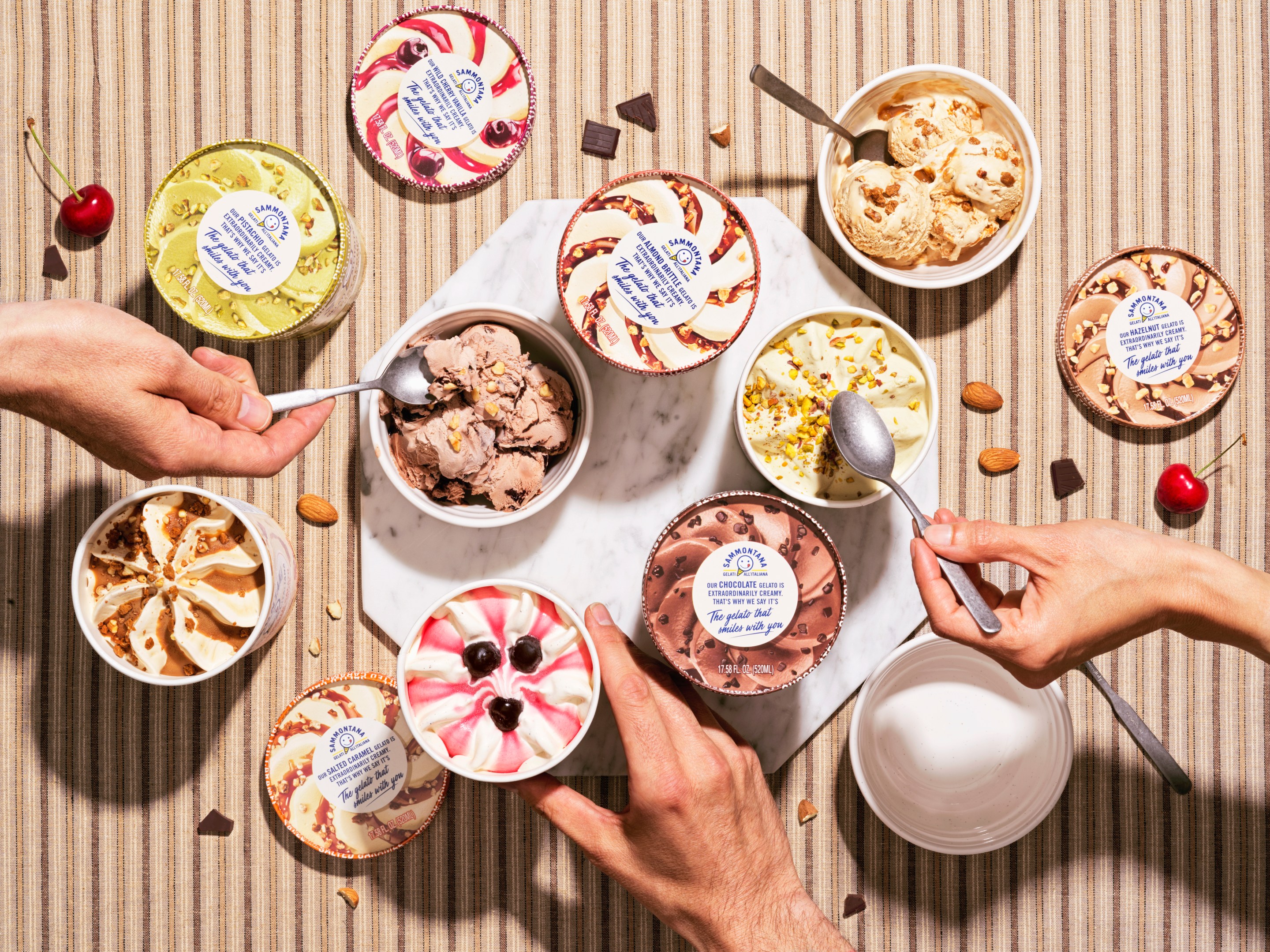 Multiple pints in various flavors, with hands and spoons reaching in.