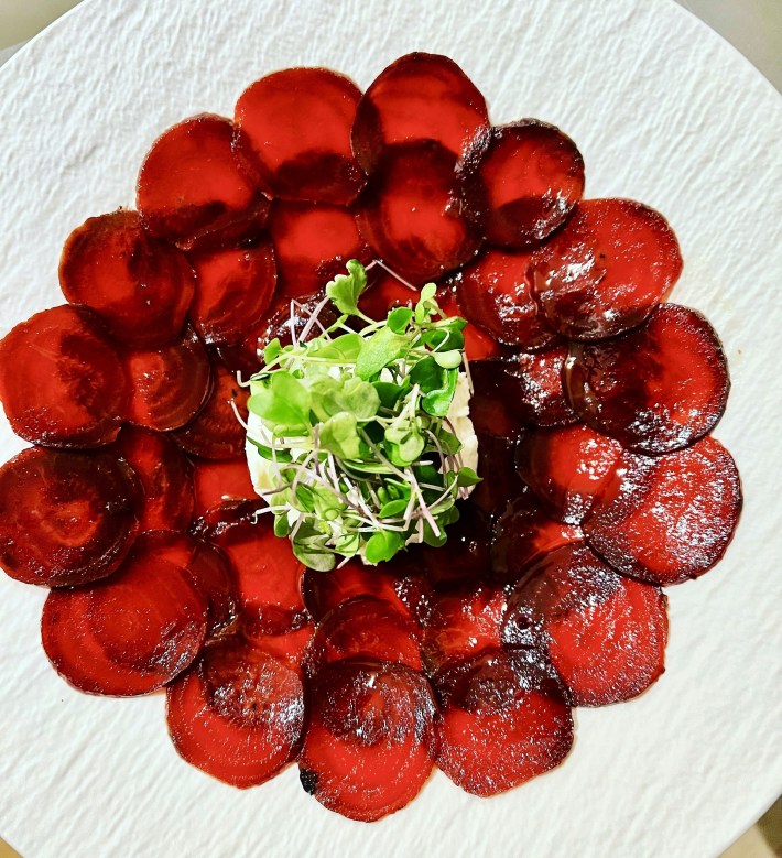 Plate of thin beet slices with greens in the center.