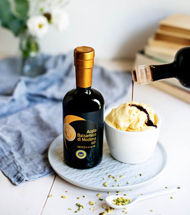 Bottle of Balsamic Vinegar of Modena PGI next to vanilla gelato topped with a drizzle of vinegar