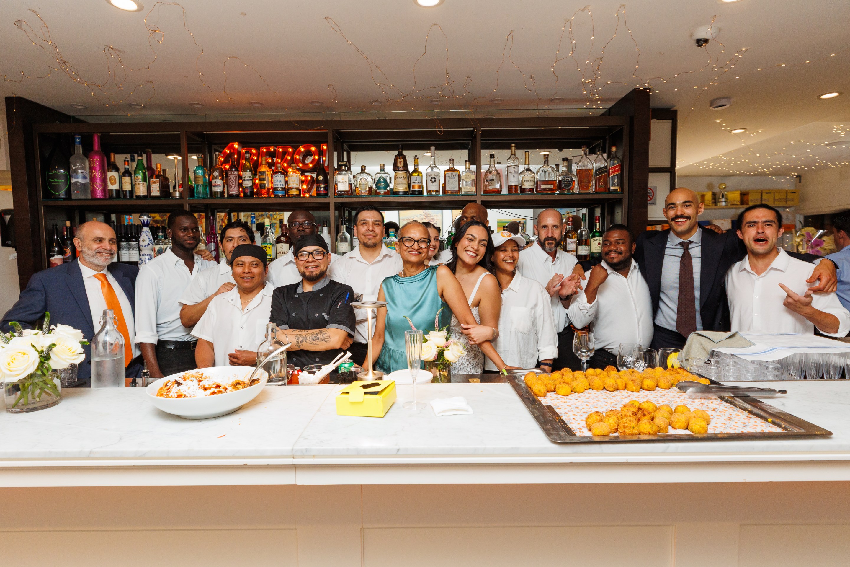 Settepani family and staff cheering behind the bar at their anniversary