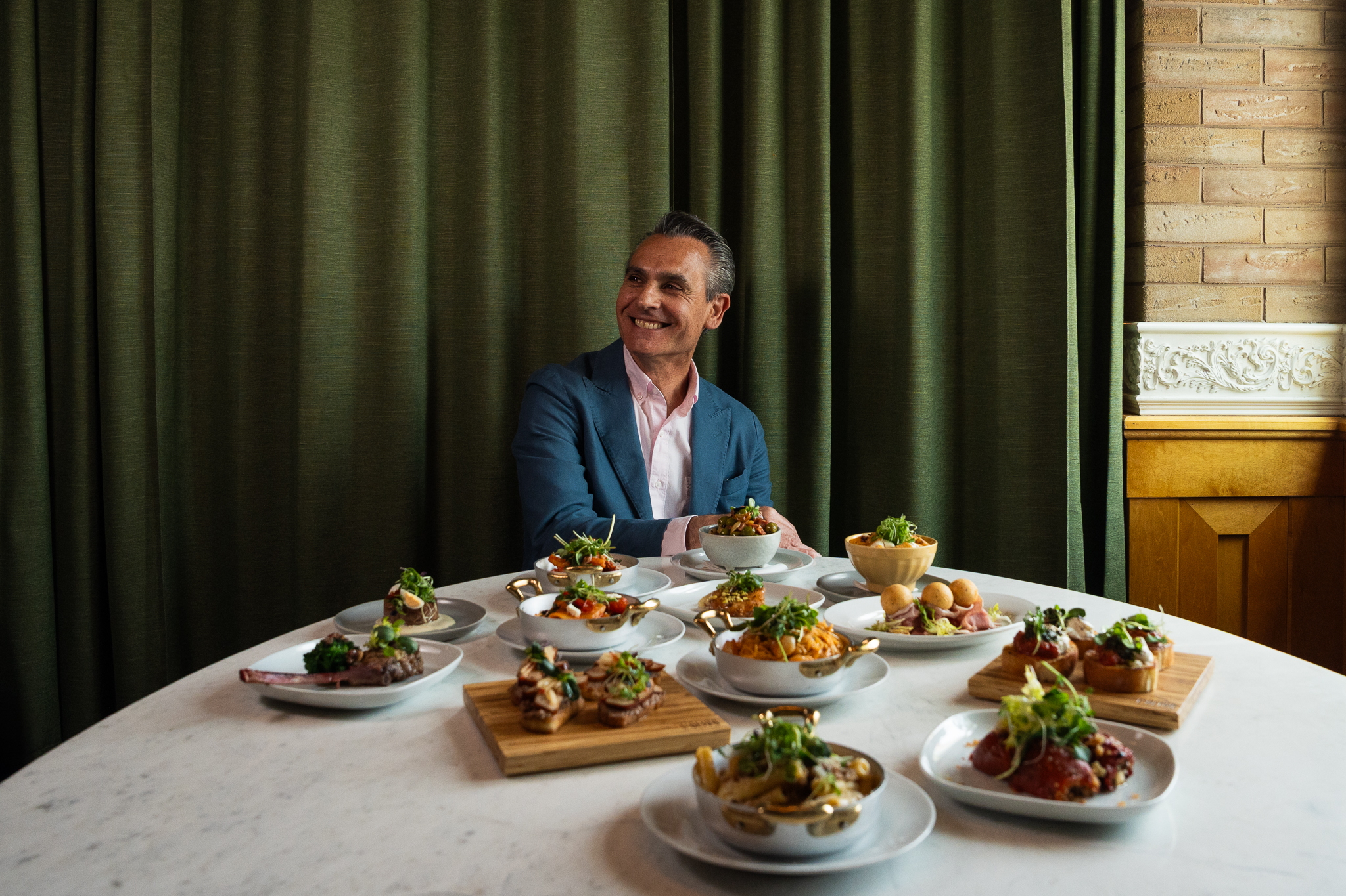 Chef Giuseppe di Gennaro seated at table with cicchetti dishes at L’Olivo