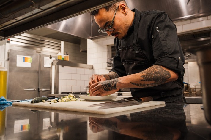 Chef plating a dish in the kitchen at L’Olivo Calgary