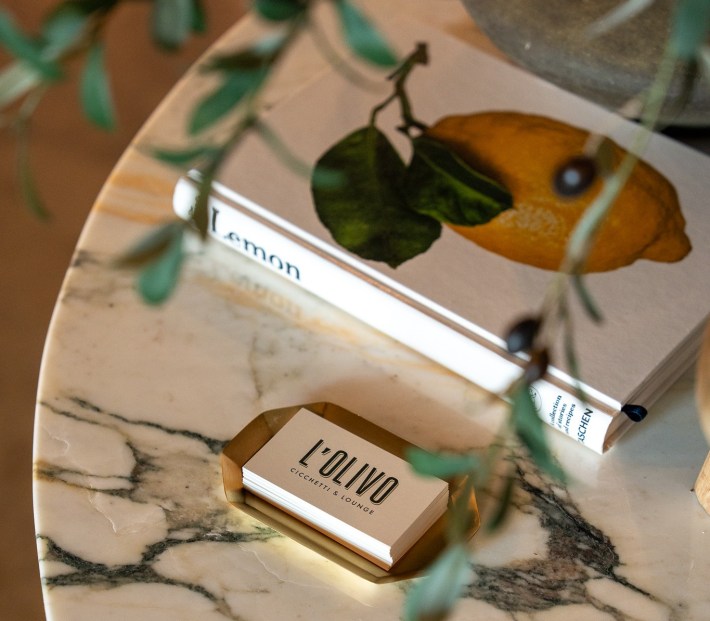 L’Olivo business cards beside lemon cookbook on marble table
