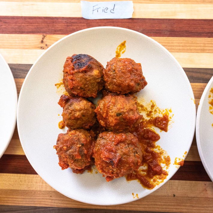 Plate of fried meatballs covered in tomato sauce.