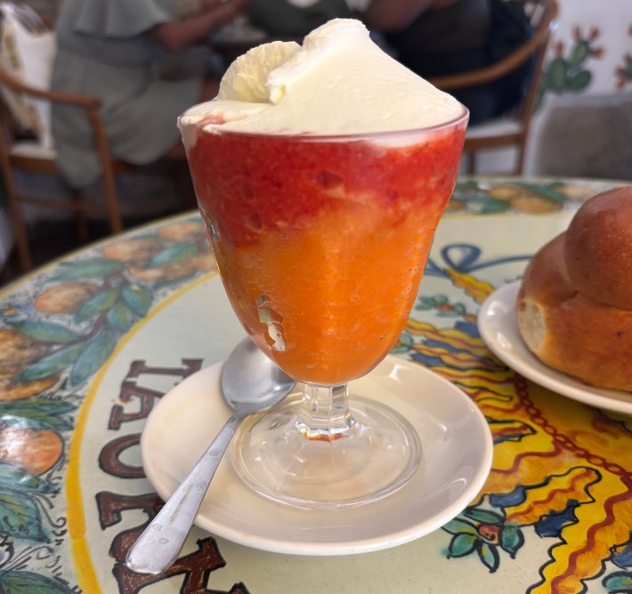 Glass of strawberry and blood orange granita with whipped cream and brioche