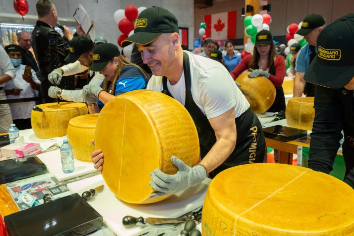 Chef David Rocco lifting a Parmigiano Reggiano wheel at cracking event in Toronto