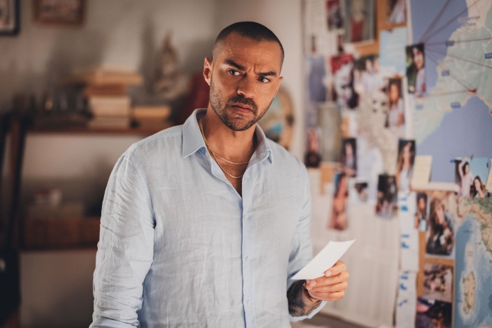 Jesse Williams in a scene from Hotel Costiera examining a photo