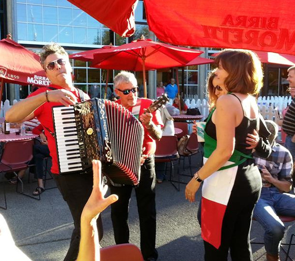 Musicians play accordion and guitar under red umbrellas at Seattle’s Festa Italiana