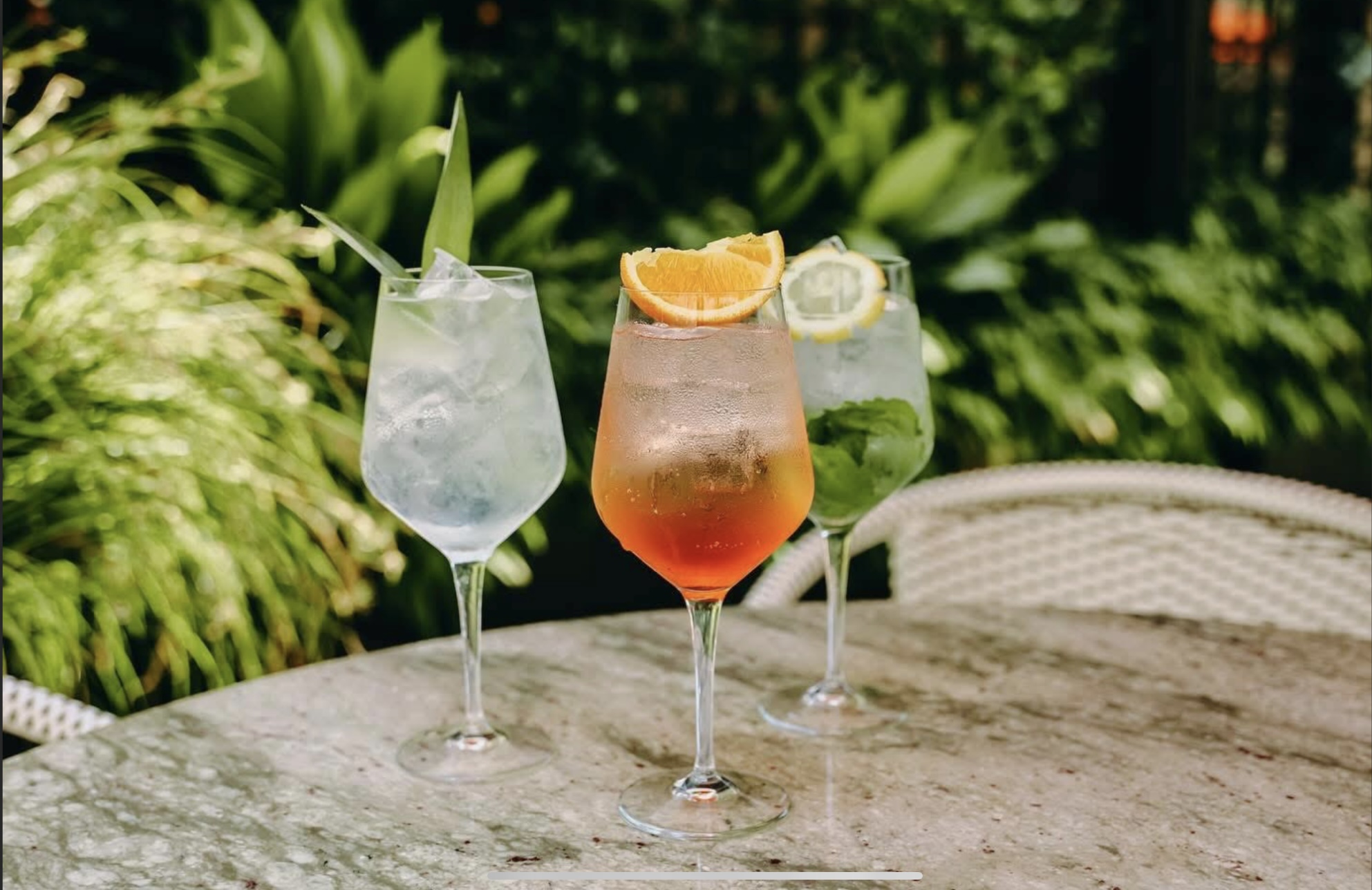 Three colorful spritz cocktails on a marble outdoor table at Frannie & The Fox Charleston